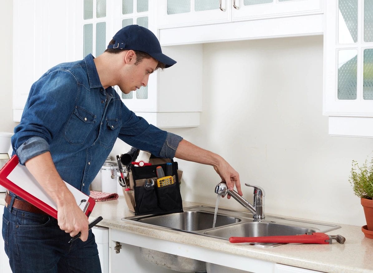 A man is fixing the faucet of his kitchen sink.